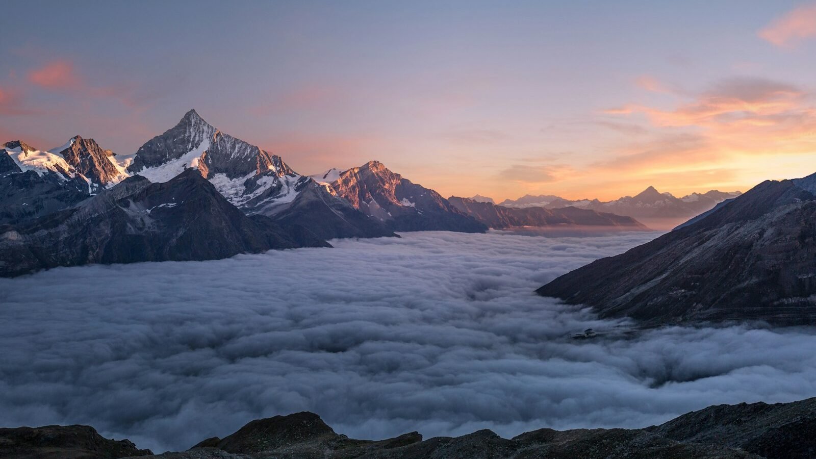 A hiker standing on a mountain ridge at sunrise