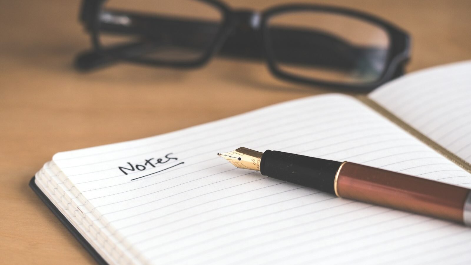 An open notebook with handwritten notes beside a pen